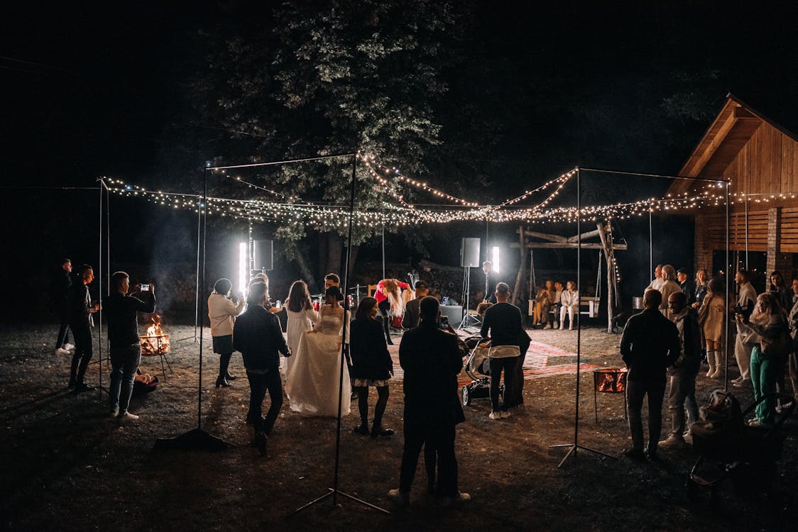 Newlyweds and wedding guests celebrating at an outdoor reception at night